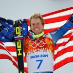 Winner Ted Ligety of the U.S. holds up his national flag during the flower ceremony for the men's alpine skiing giant slalom event in the Sochi 2014 Winter Olympics at the Rosa Khutor Alpine Center